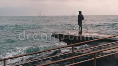 忧郁的小男孩站在码头。 孤独的男孩看着<strong>风雨</strong>飘摇的大海。 海上悲观的人码头。 黑暗中的小男孩